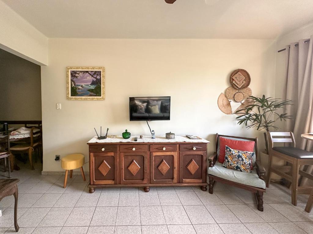 a living room with a wooden cabinet and a chair at Apartamento com vista pro mar no Centro de Ubatuba - com estacionamento 2 quartos e cozinha completa in Ubatuba