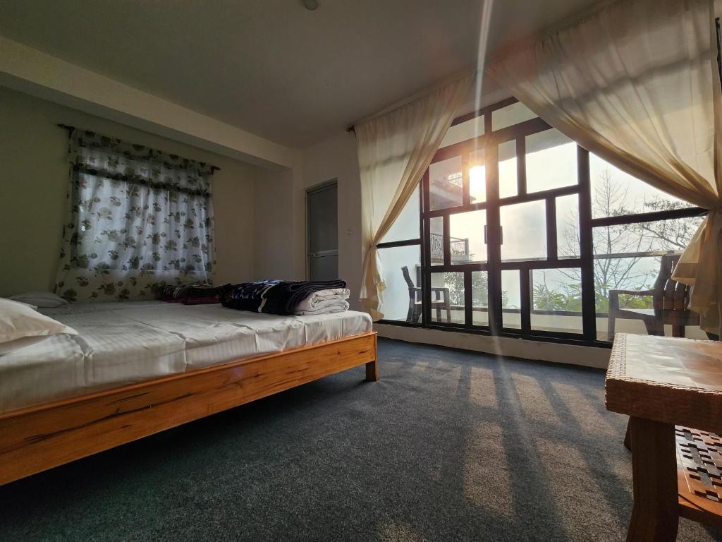 a bedroom with a bed and a large window at Jetsunma Homestay in Darjeeling