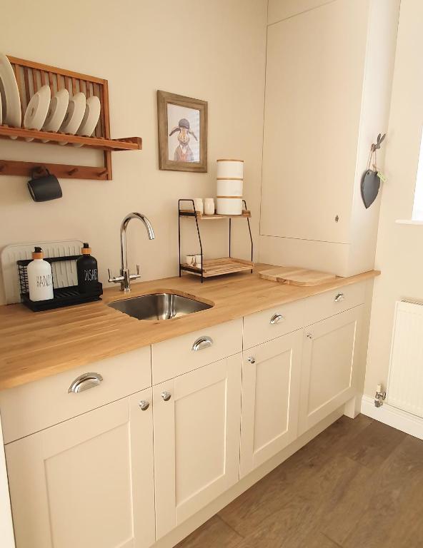 a kitchen with white cabinets and a sink at Cosy Hutch in Saxelby