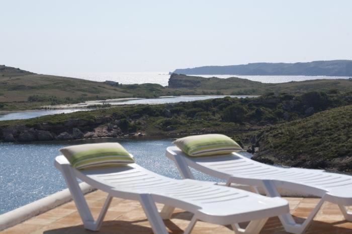 two white chairs sitting on a deck with a view of a river at CHALET BINIMASR ADDAYA in Port d'Addaia