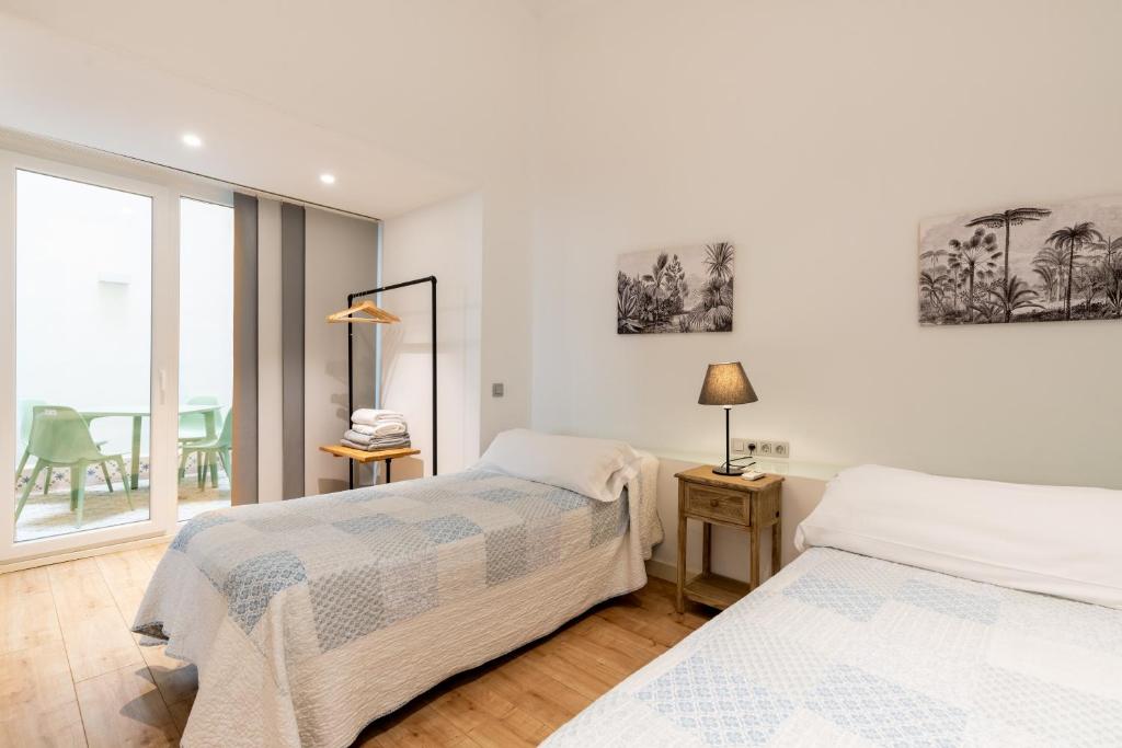 2 łóżka w białym pokoju z oknem w obiekcie Apartamentos Lanza w Sewilli