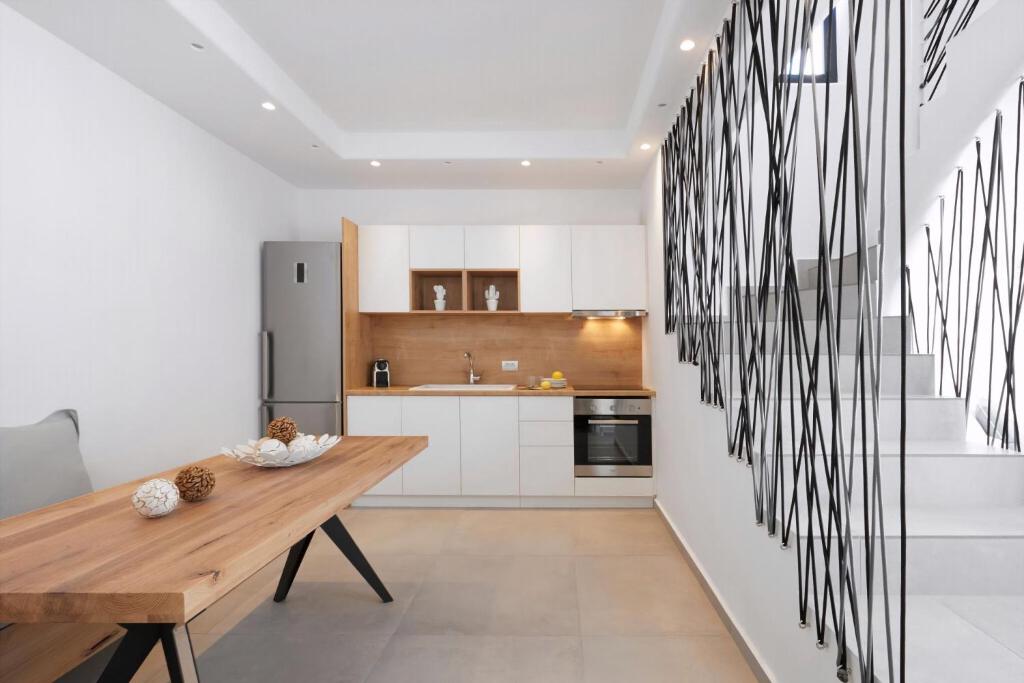 a kitchen with a wooden table and a refrigerator at Lovely Santorini Villa 3 Bedrooms Villa Petra Private Pool & Outdoor Dining Area Exo Gialos in Karterados