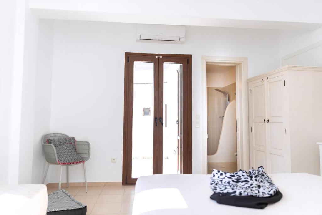 a white bedroom with a bed and a chair at Naxos Central Room Superior Triple Room Balcony 200M From St George Beach City Views Saint George in Naxos Chora