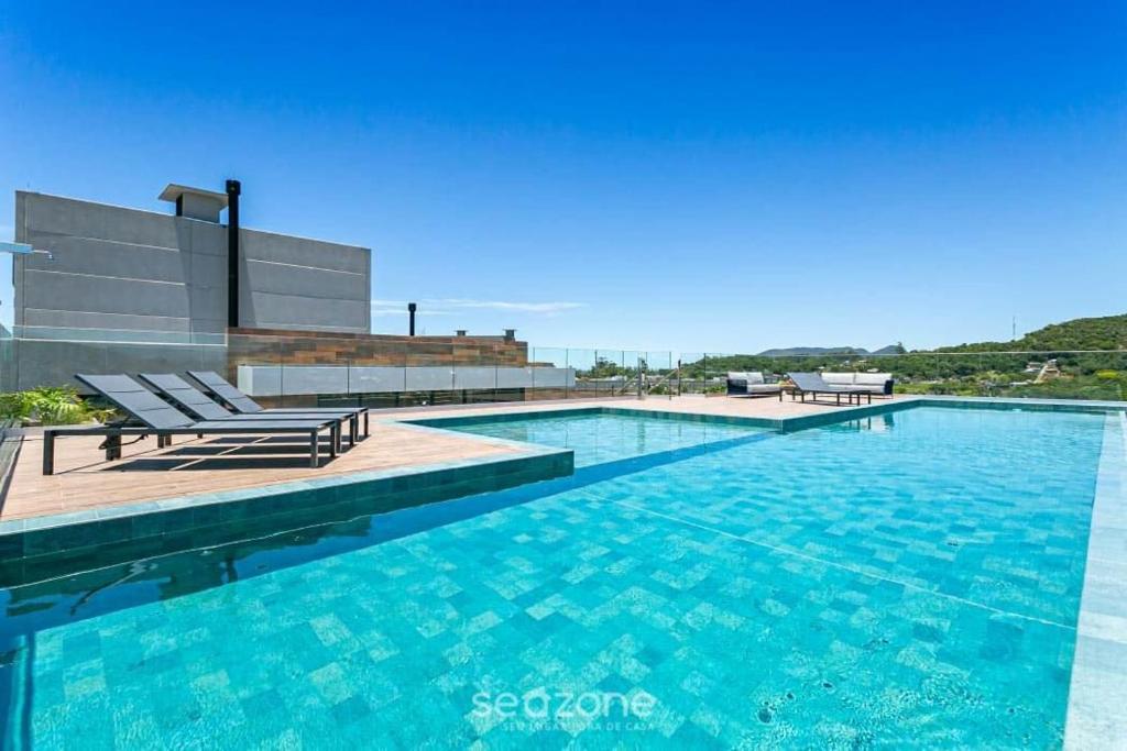 a swimming pool with two lounge chairs next to a building at Studios aconchegantes em Floripa - OKA in Florianópolis