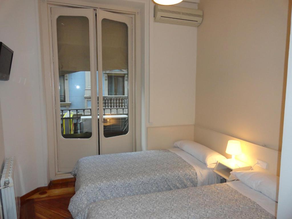 a hotel room with two beds and a window at Hostal Alistana in Madrid