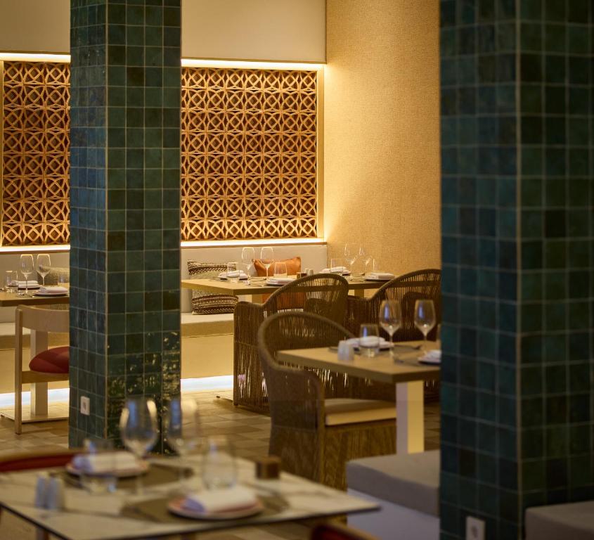 a restaurant with tables and chairs and green tiled walls at Cala San Miguel Ibiza Resort, Adults only, Curio Collection by Hilton in Puerto de San Miguel