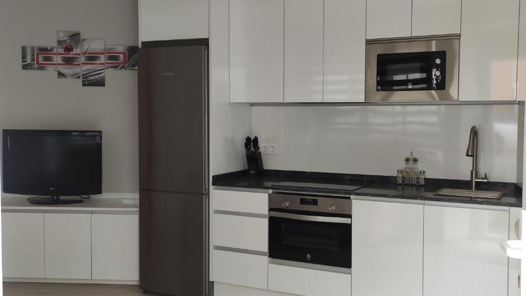 a kitchen with white cabinets and a black stove and a tv at Entrepuertos in Foz