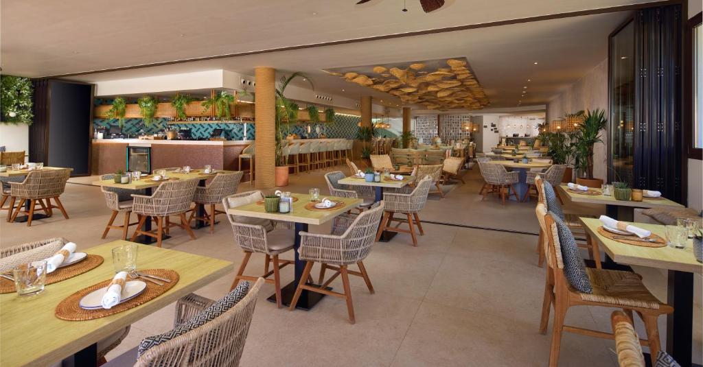 a restaurant with tables and chairs and a counter at Cala San Miguel Ibiza Resort, Adults only, Curio Collection by Hilton in Puerto de San Miguel