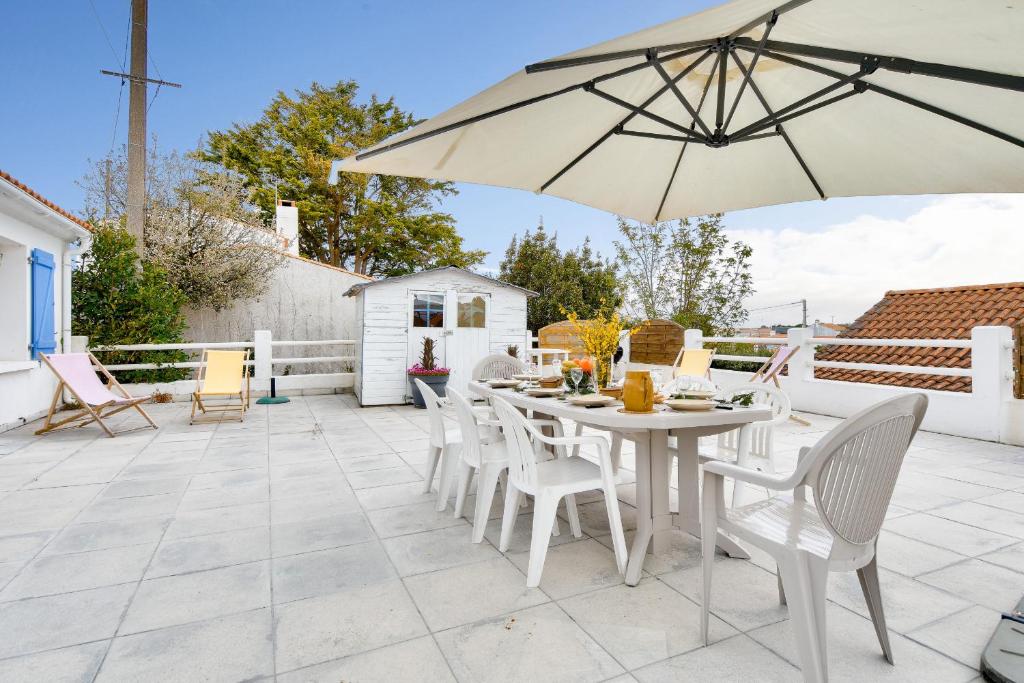 a white table and chairs with an umbrella on a patio at Maison à Barbâtre pour 10 - 450m de la plage in Barbâtre