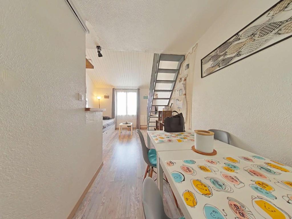 une pièce avec une table, des chaises et un escalier dans l'établissement Studio Mezzanine Lumineux avec Wifi, Idéalement Situé, 4 Couchages, à 250m de la Plage et du Port - FR-1-224B-99, à Noirmoutier-en-l'lle