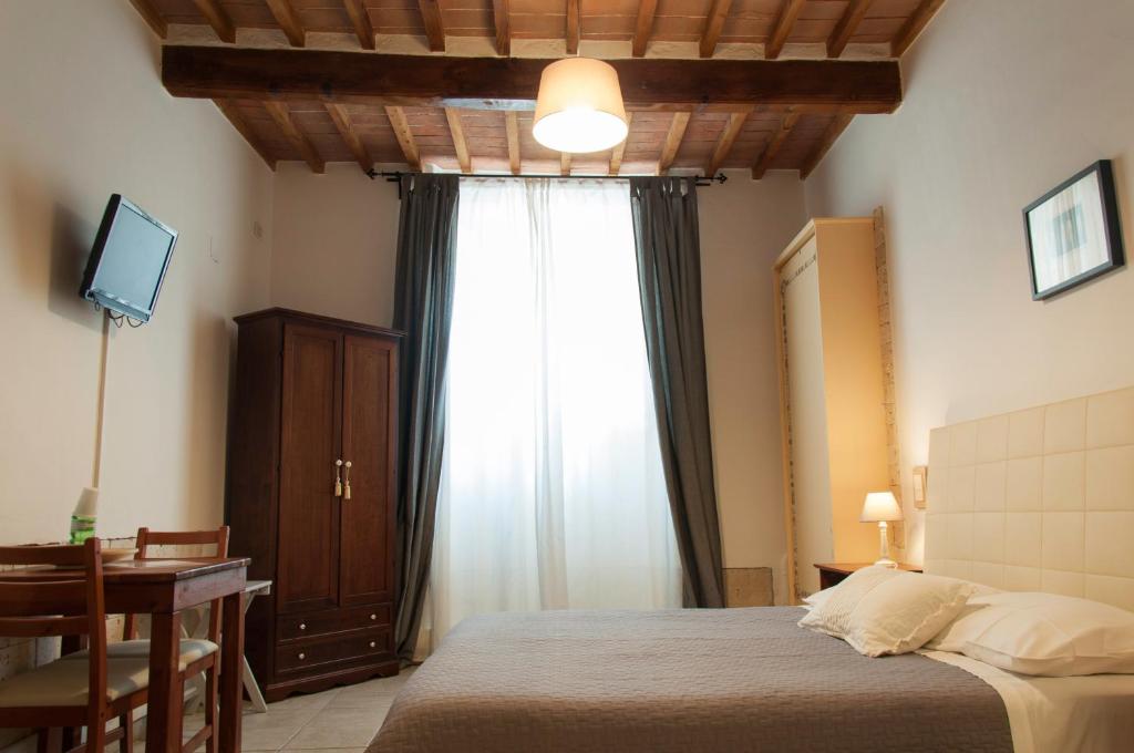 a bedroom with a bed and a desk and a window at Bed & Tower in Pisa