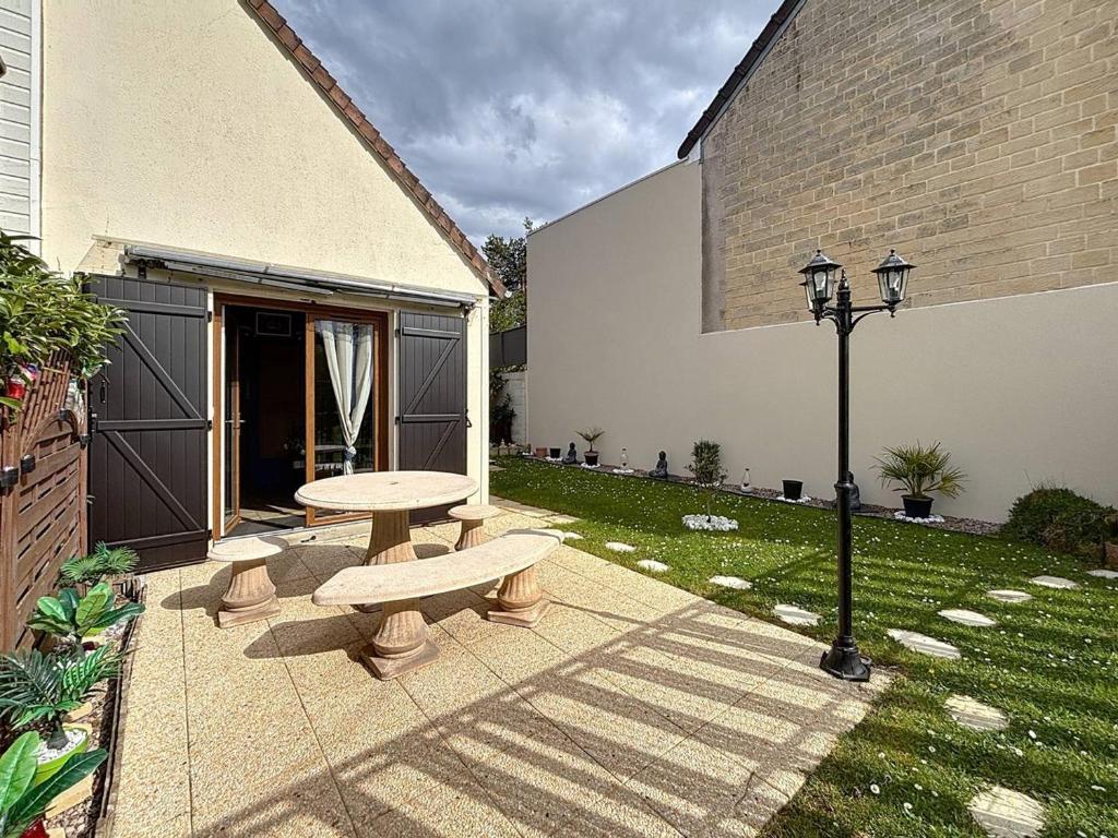d'une terrasse avec une table de pique-nique et un éclairage de rue. dans l'établissement Duplex avec Jardin Privé pour 4 Pers. à 400m de la Plage - Merville-Franceville - FR-1-465-110, à Merville-Franceville-Plage