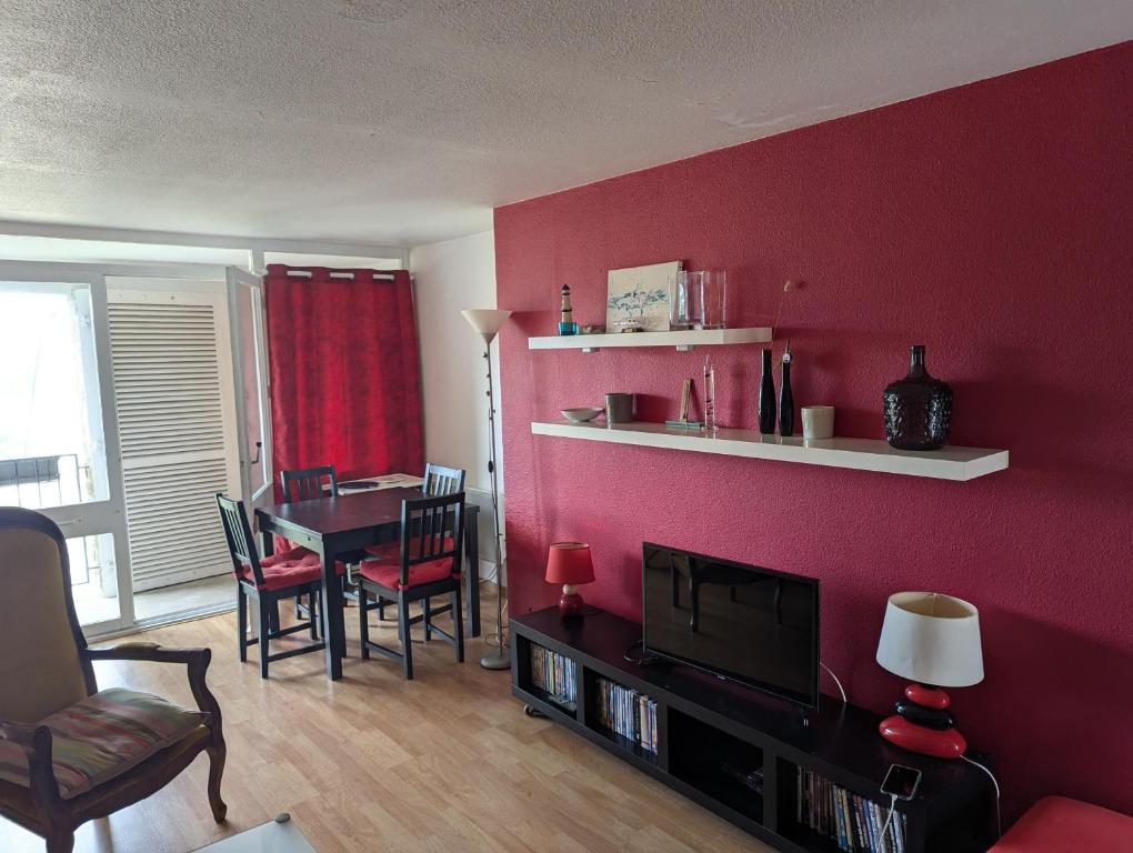 - un salon avec un mur rouge, une table et des chaises dans l'établissement Ref 065 Appartement duplex pour sept personnes plage à pied Arzon, à Arzon