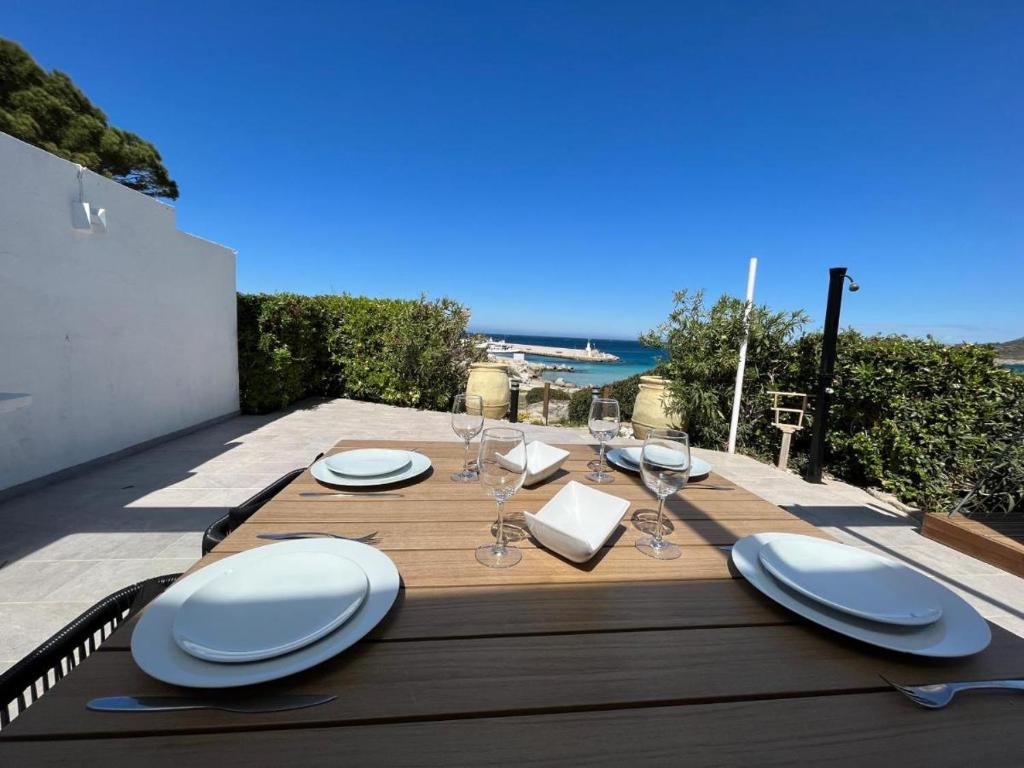 une table en bois avec des assiettes et des verres à vin dessus dans l'établissement PIEDS DANS l EAU A SANT AMBROGGIO, à Lumio