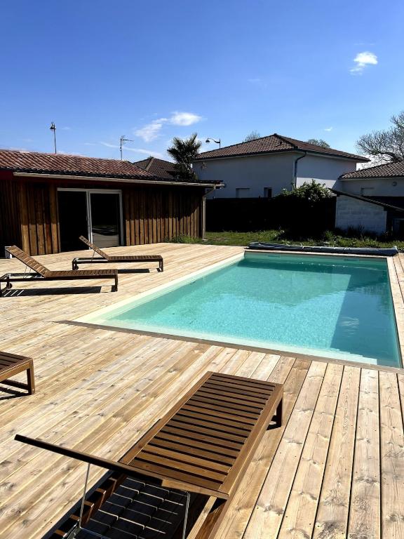 une piscine avec une terrasse en bois et une maison dans l'établissement Maison Poulette, à Tosse