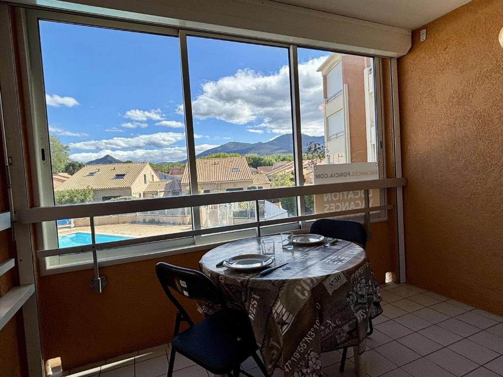 une table et des chaises dans une pièce avec une grande fenêtre dans l'établissement Appartement T2 avec piscine, loggia, parking privé - 800m plage, Argelès-sur-Mer - FR-1-225-209, à Argelès-sur-Mer