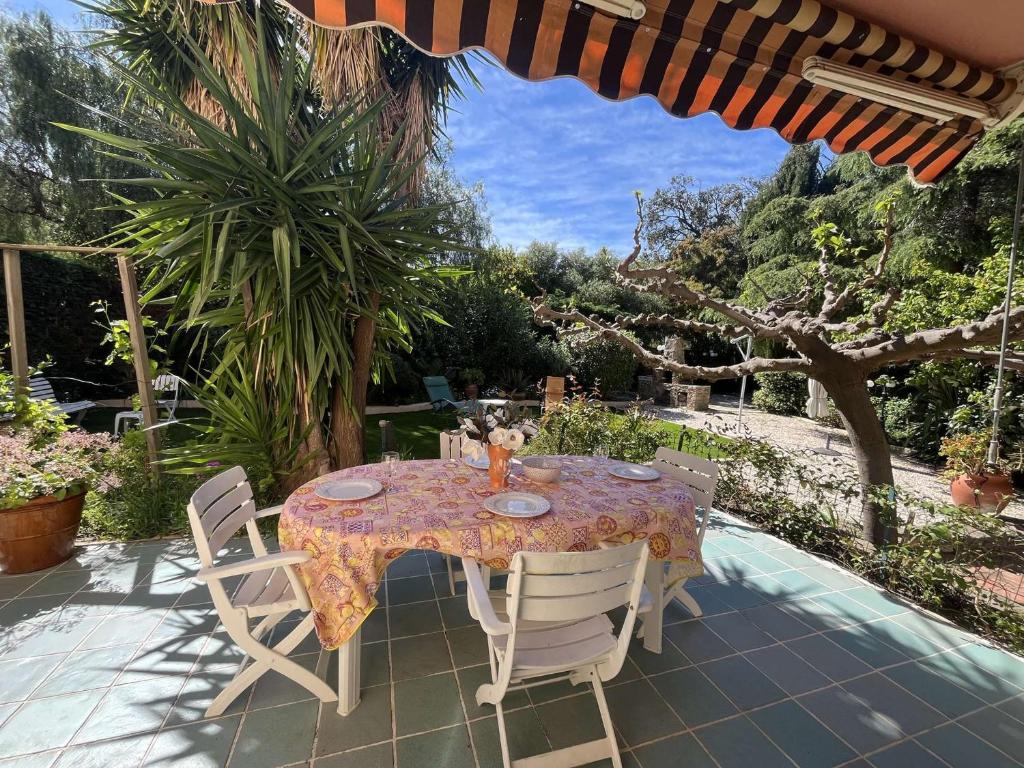 une table avec des chaises et un parasol sur une terrasse dans l'établissement Appartement cozy 2 pièces avec jardin, climatisation et équipements complets - Le Lavandou - FR-1-308-115, au Lavandou