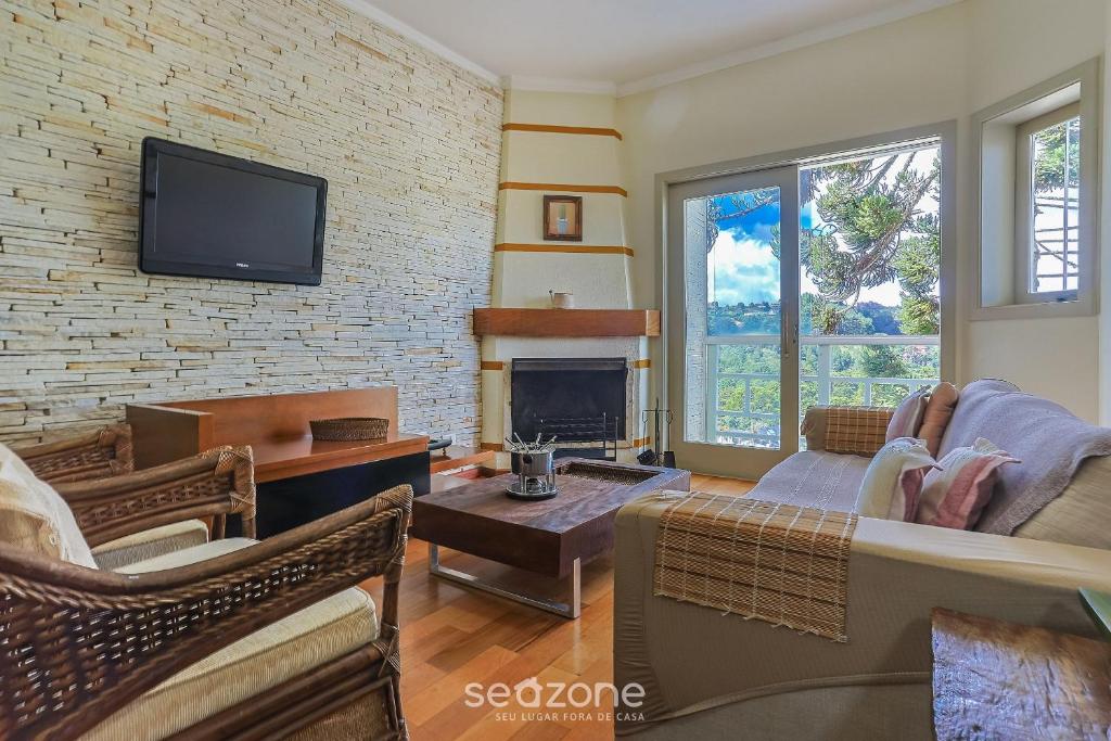 a living room with a fireplace and a tv at Apto c/ Linda Vista em Campos do Jordão LVR0003 in Campos do Jordão