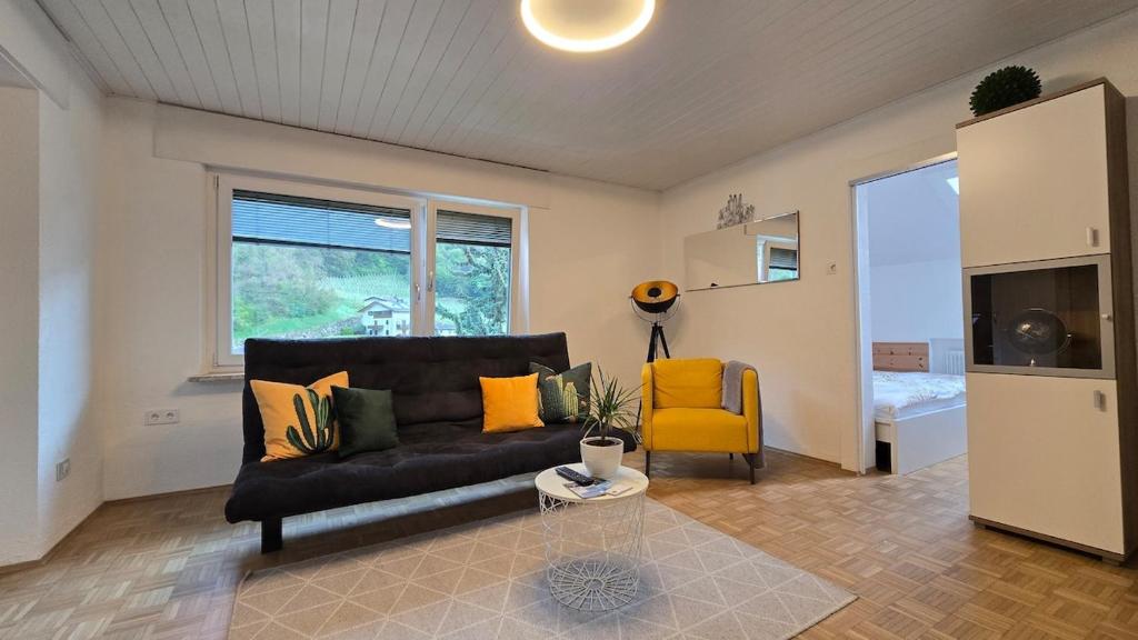 a living room with a black couch and a yellow chair at Hike, Bike & More in Parcines