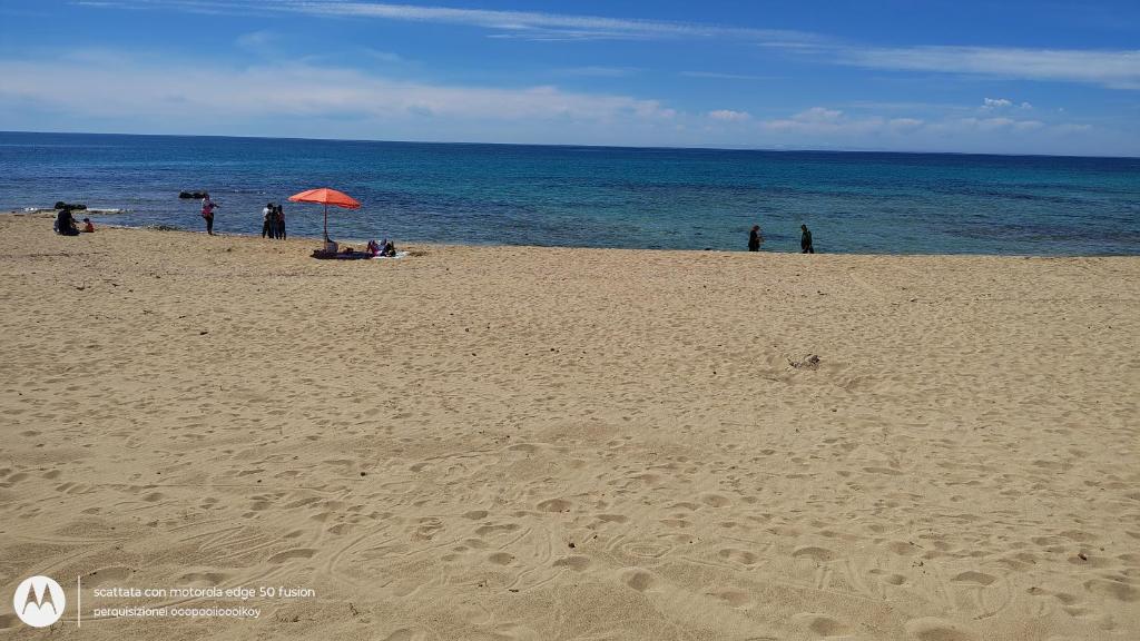 a group of people on a beach with an umbrella at Il Risveglio delle Onde 2 in Torre Ovo