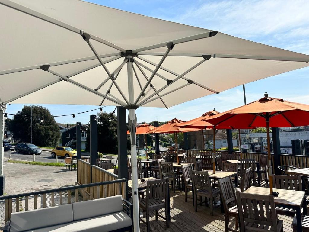 a large white umbrella on a patio with tables and chairs at Downs Hotel in Stanmer