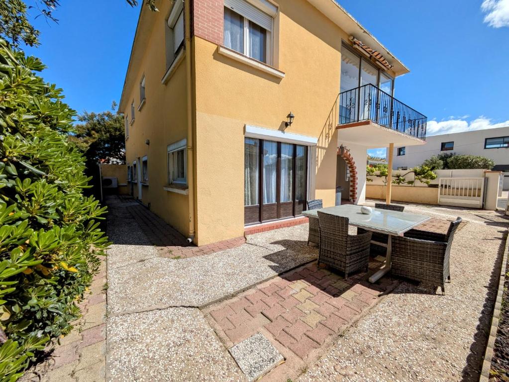 un patio avec une table devant une maison dans l'établissement Les Tulipes - T3 rénové avec parking, terrasse et climatisation, à Canet