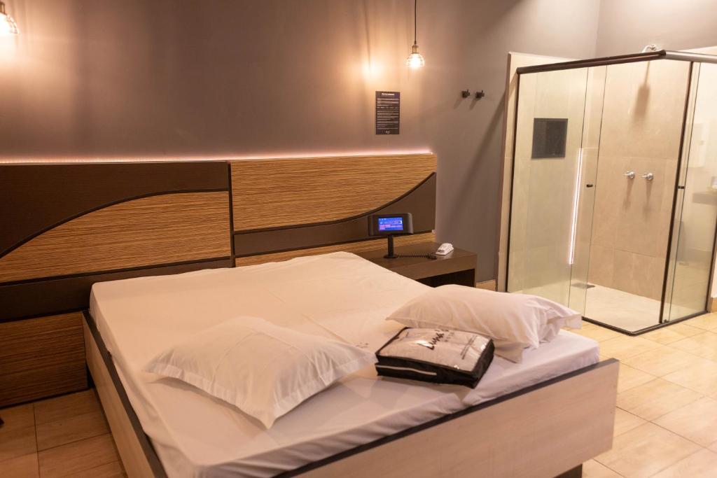 a bedroom with a bed with a glass shower at Luna's Motel in Sumaré