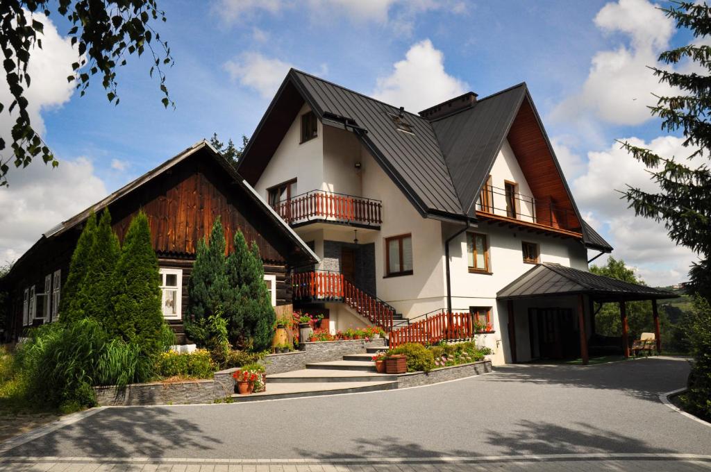 a large white house with a black roof at Wiśniowy Gaj in Ujanowice