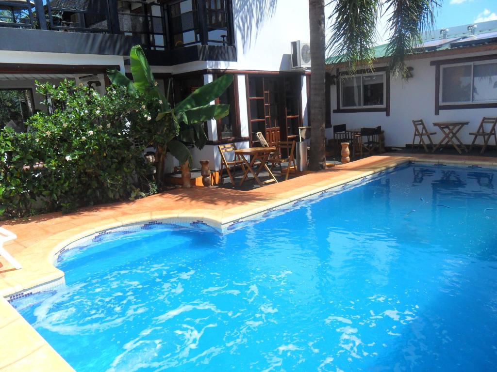 a large blue swimming pool next to a house at Si Mi Capitán - Cabañas & Habitaciones in Puerto Iguazú