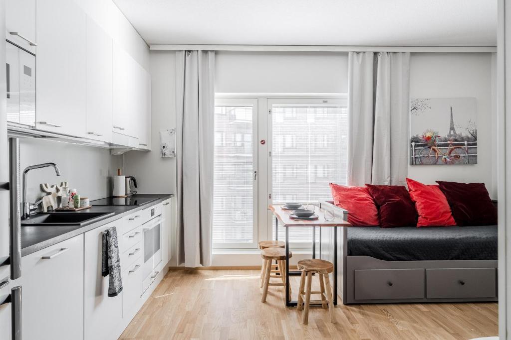 a kitchen with a bed and a table with red pillows at 28m2 condo & own parking place indoors in Turku