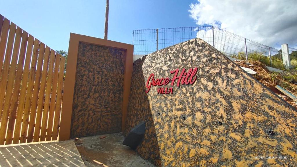 a wall with a sign on it next to a fence at Grace Hill Villa Lubuk Minturun in Padang