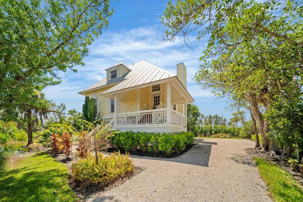 a yellow house with a white porch and trees at Gone Coastal in Sanibel