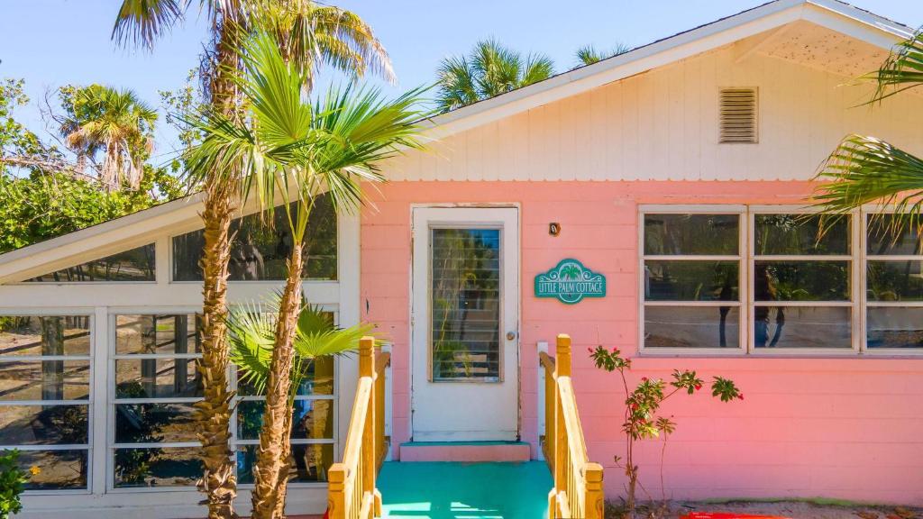 a pink house with palm trees in front of it at Little Palm Cottage in Sanibel