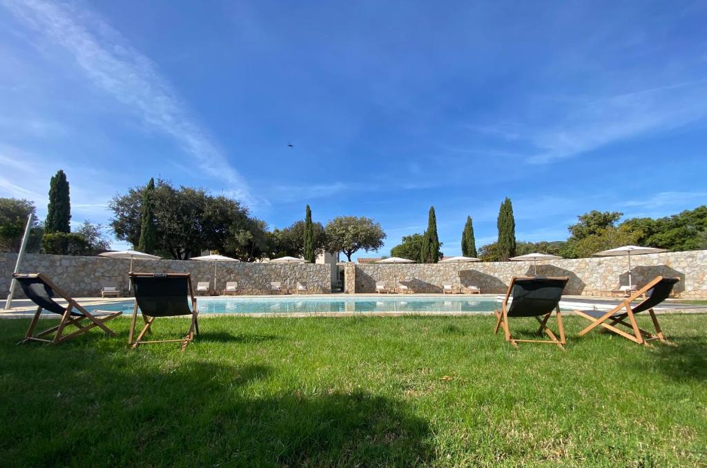 2 chaises assises dans l'herbe à côté d'une piscine dans l'établissement Les bois de Capra Scorsa, à Belgodère