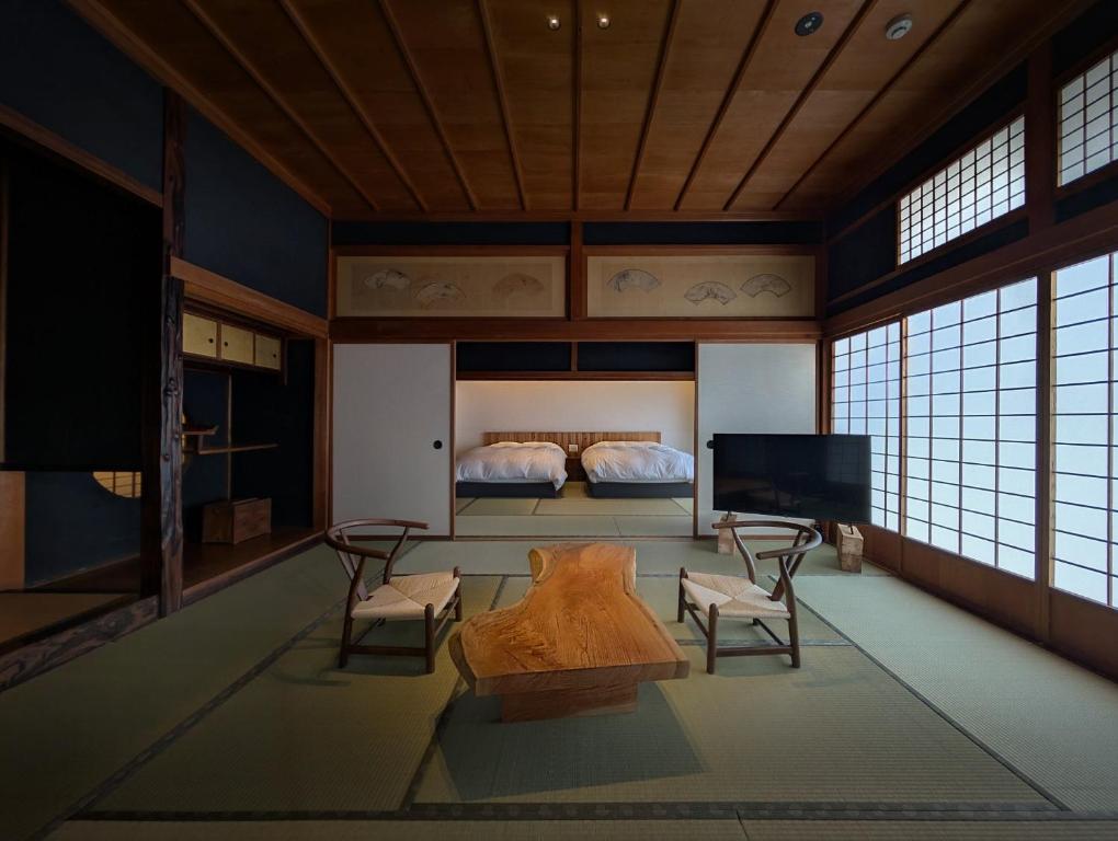 a room with a bed and a tv and a couch at 古民家ラグジュアリーホテル 金井西洋館 in Sado