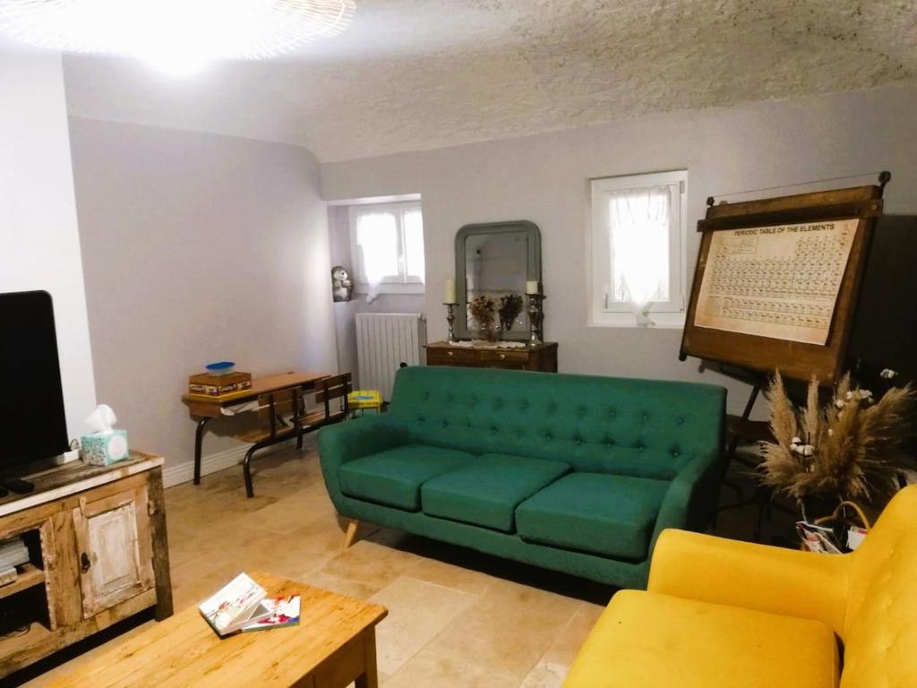 a living room with a green couch and a tv at Maison de caractère 170m2 coeur de village in Saint-Montan