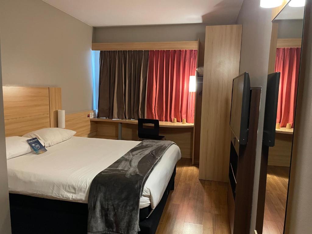 Un dormitorio con una cama y un televisor de pantalla plana. en ibis Santiago Estacion Central, en Santiago