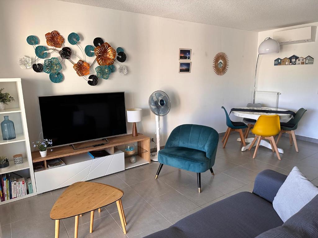Il comprend un salon doté d'une télévision, de chaises et d'une table. dans l'établissement Superbe T3 proche remparts 2 places de parking, à Aigues-Mortes