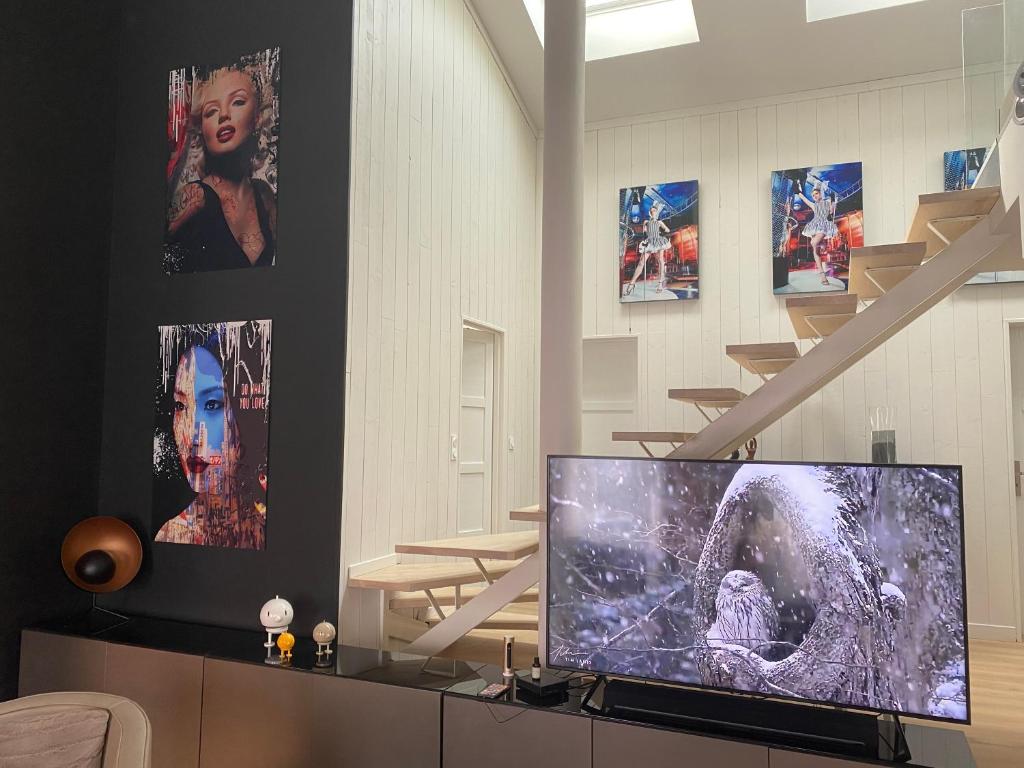 ein Wohnzimmer mit Fernseher und einigen Bildern in der Unterkunft Parker city in Saint-Gelais