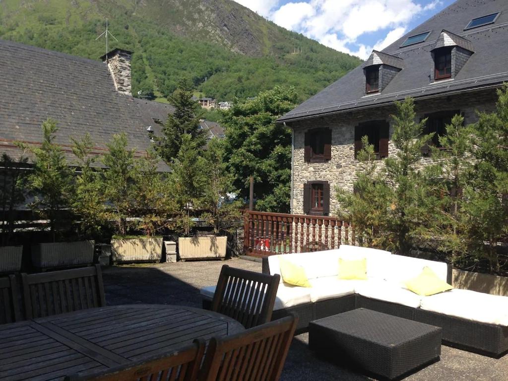eine Terrasse mit einem weißen Sofa und Stühlen und einem Haus in der Unterkunft Appartement La Foncière in Saint-Lary-Soulan