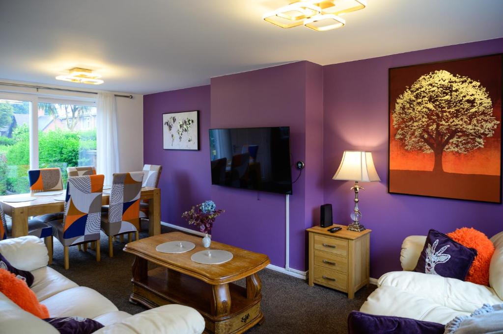a living room with purple walls and a tv at Strelley house 4 , Perfect for business trip & Families holiday or working proffesionals-5 min from M1 J25 , 500MB Wi-Fi , Netflix , Fully equiped kitchen , Asda supermarket 5 min walk , Free Secure parking with CCTV ,available monthly deals in Nottingham