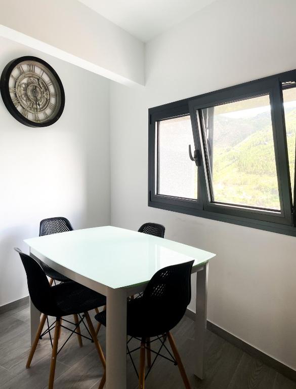 a white table and chairs in a room with a clock at Royal House AL in Rio Caldo