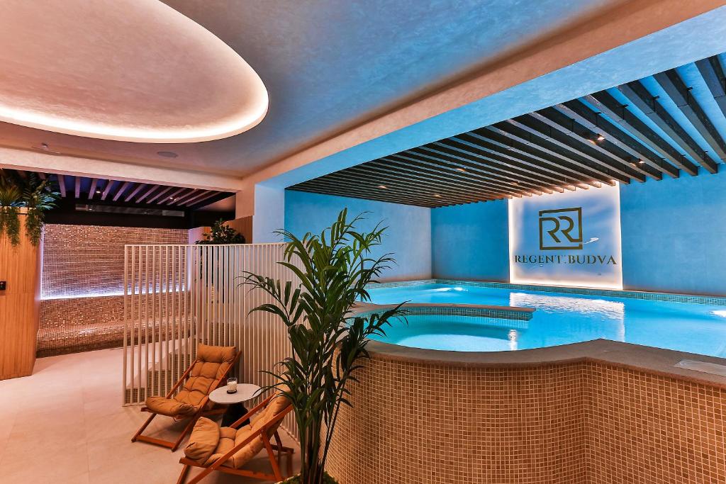 a room with a swimming pool with a table and chairs at Regent Resort Budva in Budva