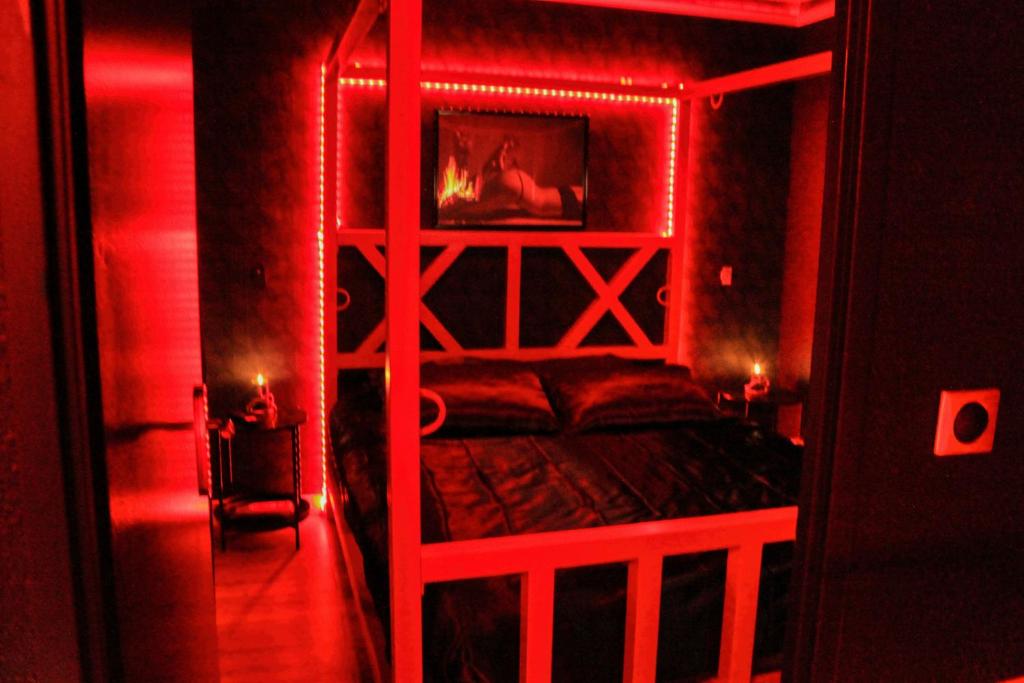 a red room with a bed with a wooden frame at Le baiser 2 Love room du plaisir interdit in Saint-Arnoult