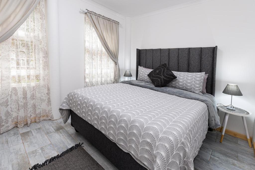 a bedroom with a bed with a black and white comforter at Die Kant - Hooggety in George