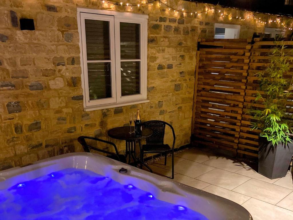 a bath tub in a room with a table at Tranquil retreat with hot tub in Stoke Bruerne