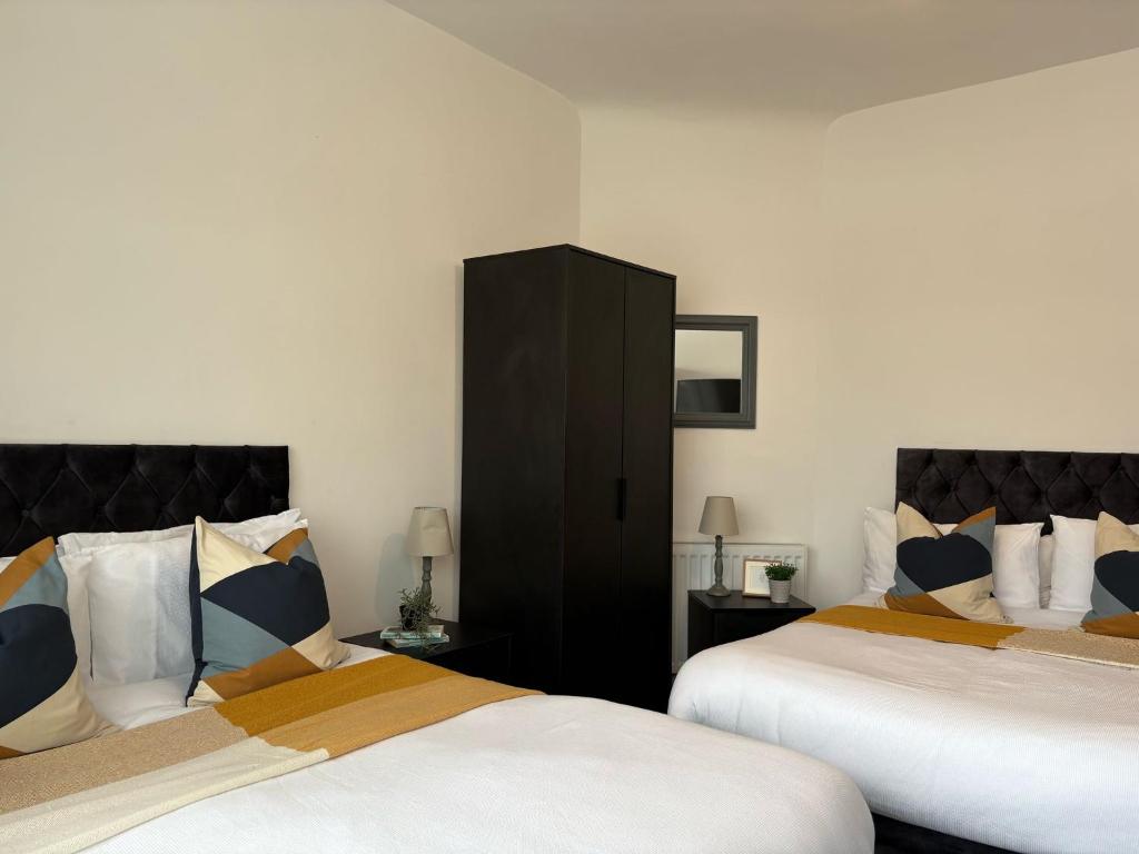 una camera con due letti e un armadio nero di Spacious Bungalow in St Helens, 1-Min Drive to Carr Mill Bridge a Saint Helens