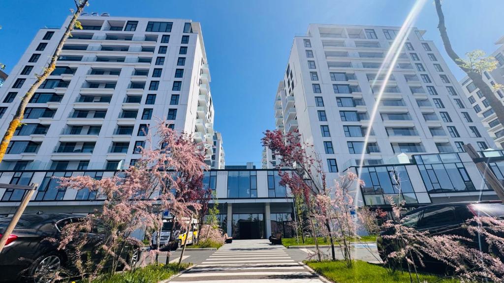 Exclusive 1BR Apartments in ONE Cotroceni في بوخارست: مبنيان بيض طويلان مع أشجار أمامهما