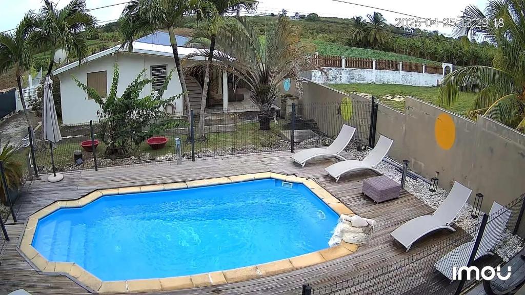 una piscina su una terrazza in legno con sedie e una casa di Villa élégante à Saint-François + Piscine privée ouverte toute l’année a Saint-François