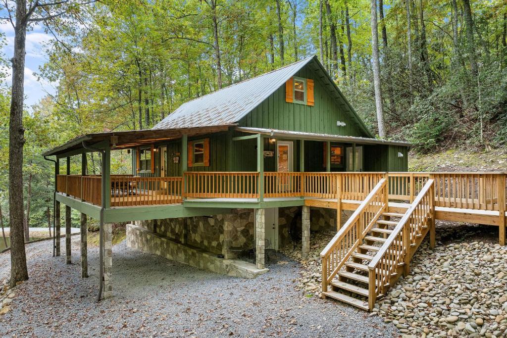 una casa verde con una gran terraza en el bosque en Beside Still Water 1, en Cosby